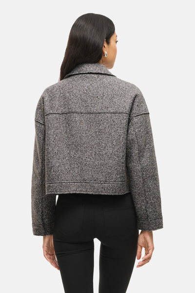 Kort grijs jasje van VILA® met zichtbare tweedtextuur, gedragen over een zwarte broek.