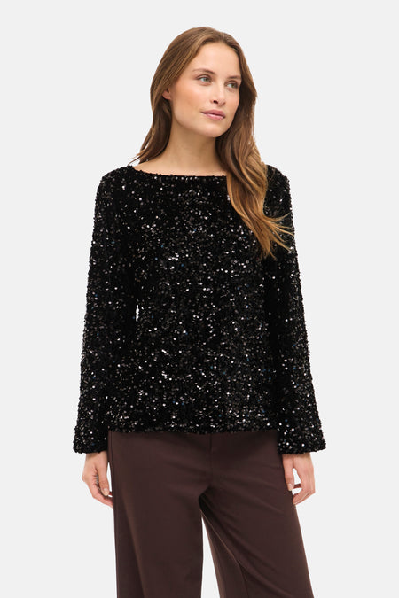 Zwarte blouse met lange mouwen van VILA®, versierd met glinsterende pailletten, gedragen met een bruine broek en sandalen.