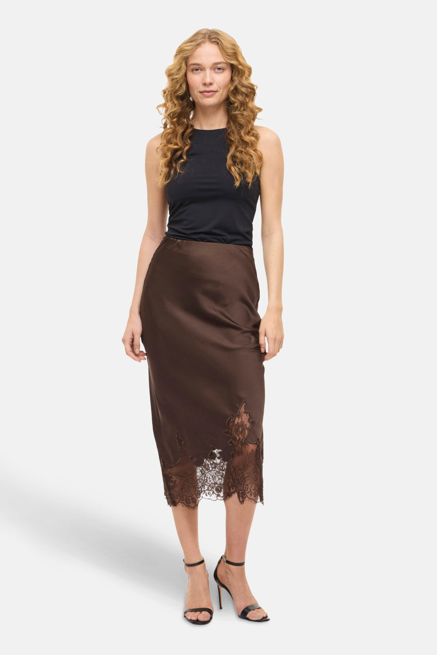 Jupe 3/4 brune de VILA®, avec bordure en dentelle florale et portée avec un haut noir uni.
