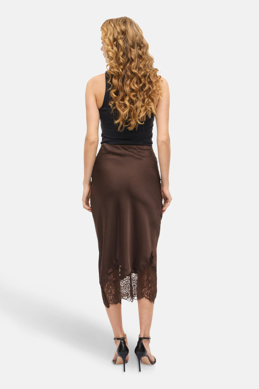 Bruine 3/4 rok van VILA®, met kanten details aan de zoom, gedragen met een zwarte tanktop en hoge hakken.