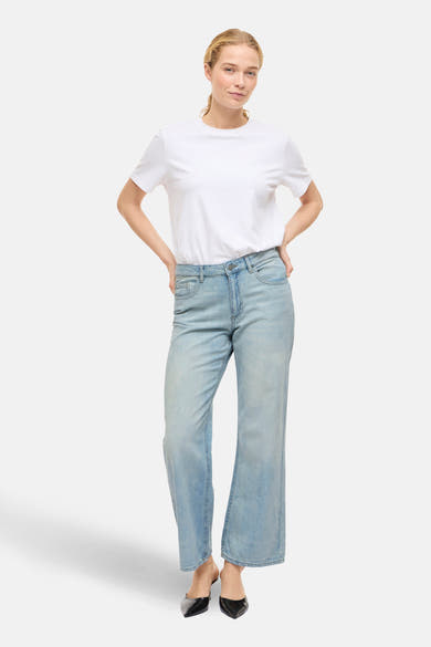 Jean large en denim bleu clair de VILA, porté avec un t-shirt blanc et des escarpins noirs pointus.
