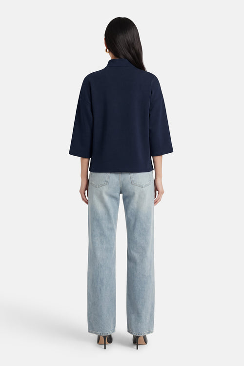 Sweat bleu de VILA®, porté avec un jean délavé et des talons noirs, vue de dos.
