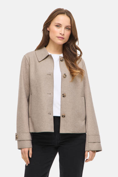 Veste courte beige par VILA, avec col tailleur et boutons apparents, portée sur un t-shirt blanc et un jean noir.