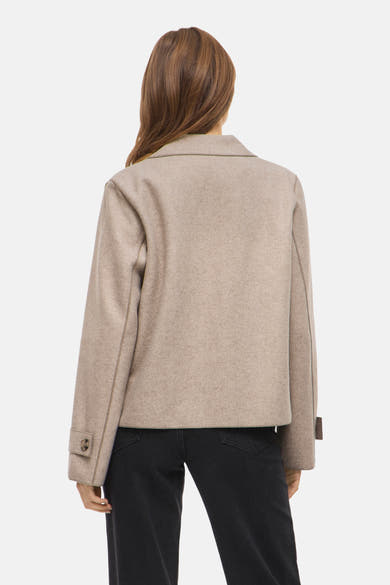 Veste courte beige de VILA®, vue de dos, avec finitions contrastantes et portée sur un jean noir.
