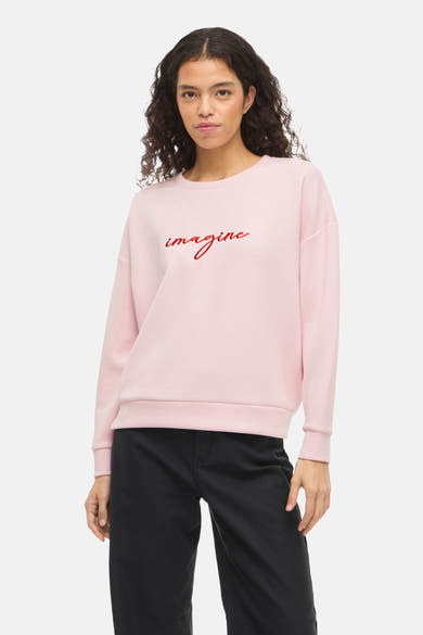 Roze sweatshirt van VILA®, met het woord 'imagine' in rood, gedragen met een zwarte broek.