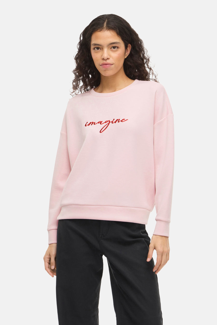 Roze sweatshirt van VILA®, met het woord 'imagine' in rood, gedragen met een zwarte broek.