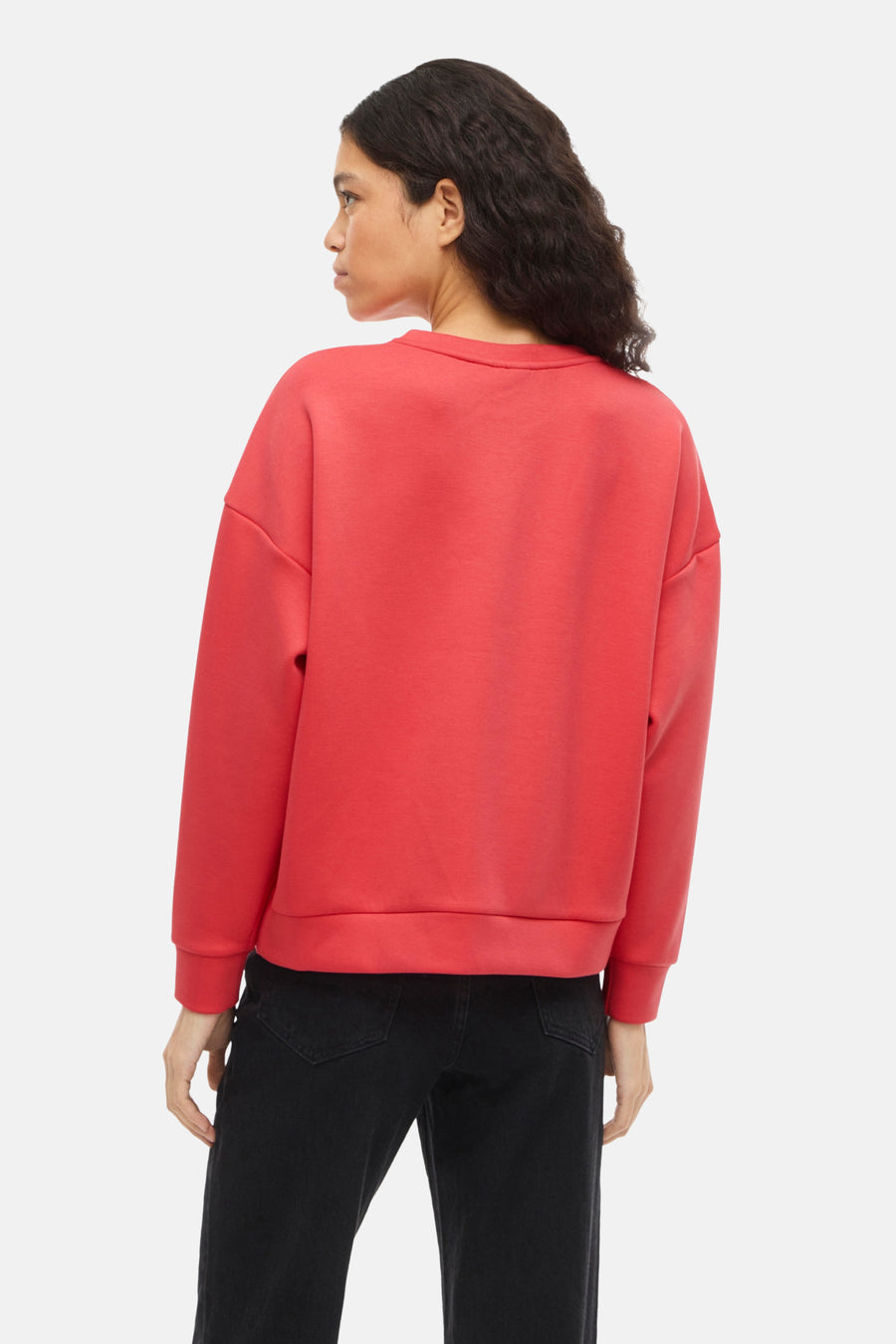 Oranje sweater van VILA, van achteren gezien, gedragen met een zwarte jeans.