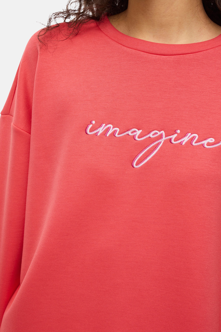 Oranje sweatshirt van VILA® met de tekst "Imagine" in roze draad op de voorkant geborduurd.