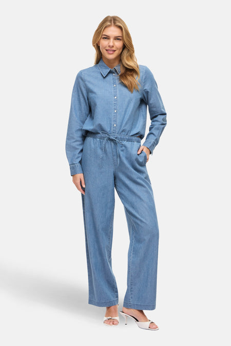 Pantalon en denim bleu clair de VILA®, avec une coupe ample et des chaussures blanches.
