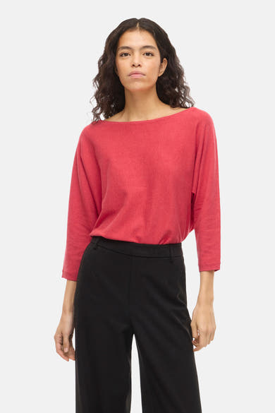 Pull à col rond rose de VILA, porté avec un pantalon noir ample.