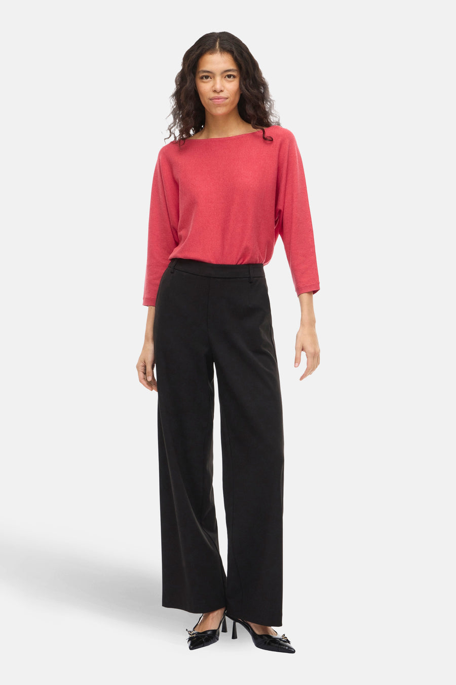 Pull à col rond rose de VILA®, manches trois quarts, porté avec un pantalon noir large et des escarpins noirs.
