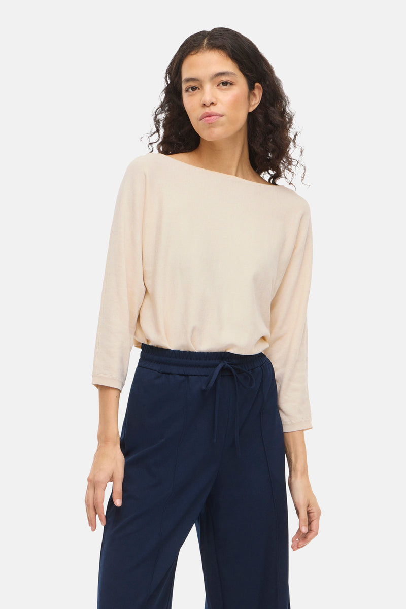 Pull à col rond beige de VILA, manches trois-quarts et coupe décontractée porté avec un pantalon bleu marine.
