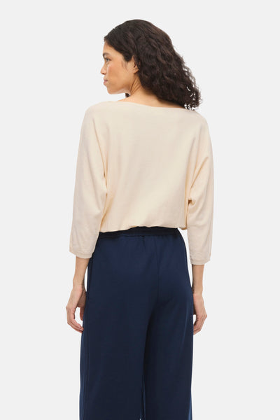 Pull à col rond beige de VILA®, porté avec un pantalon fluide bleu marine, vue de dos.
