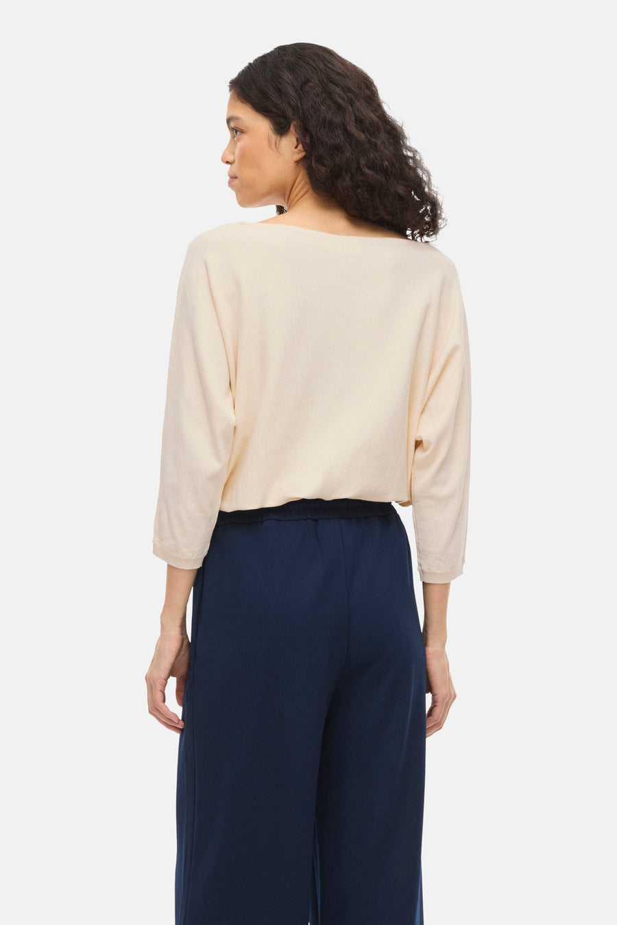 Pull à col rond beige de VILA®, porté avec un pantalon fluide bleu marine, vue de dos.
