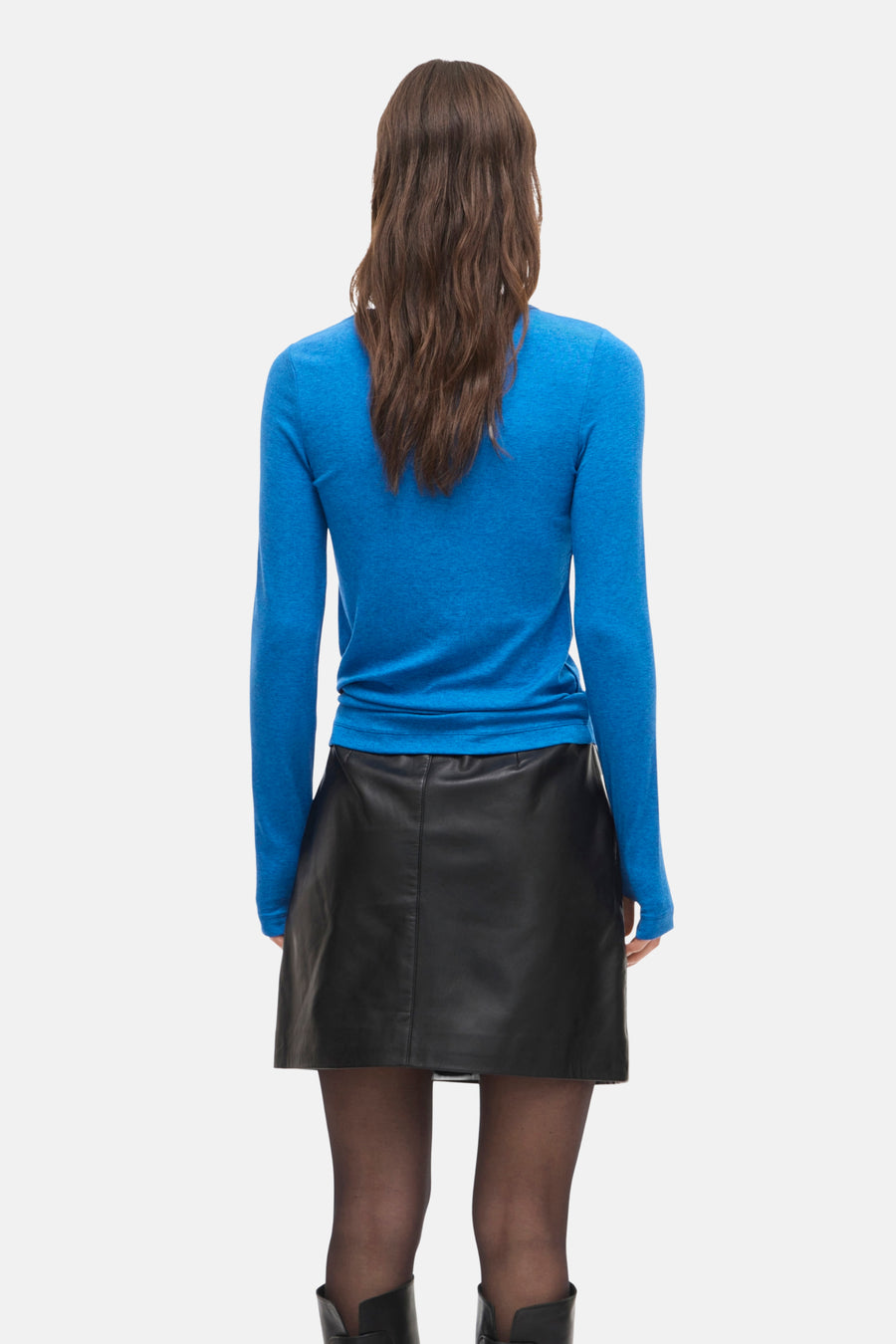 T-shirt à manches longues bleu de ROUGE EDIT, porté avec une jupe noire en cuir et des collants opaques.
