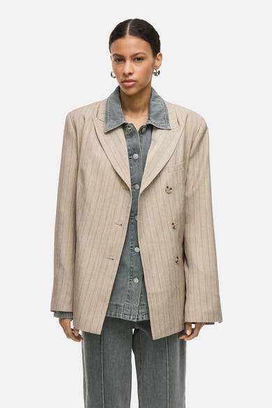 Beige blazer met fijne strepen van Rouge Edit, gedragen met een spijkerblouse en een bijpassende broek.