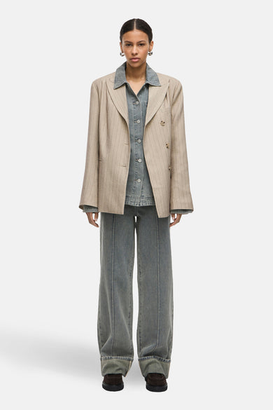 Blazer beige à rayures fines de Rouge Edit, porté avec une chemise en denim et un pantalon assorti.