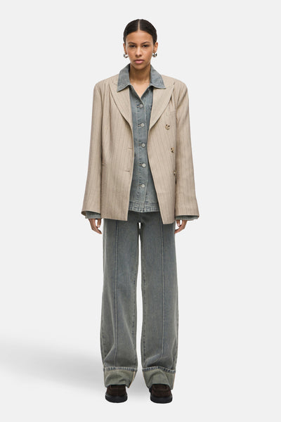 Blazer beige à rayures fines de Rouge Edit, porté avec une chemise en denim et un pantalon assorti.