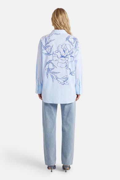 Chemise à manches longues bleue à rayures, de VILA®, avec un grand motif floral bleu dans le dos.
