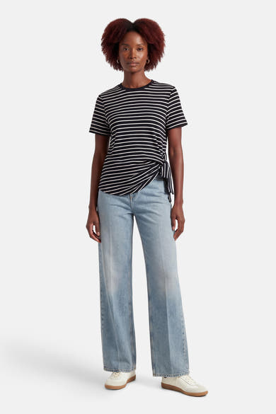 T-shirt à manches courtes noir rayé by VILA®, avec un nœud décoratif sur le côté, porté avec un jean décontracté.
