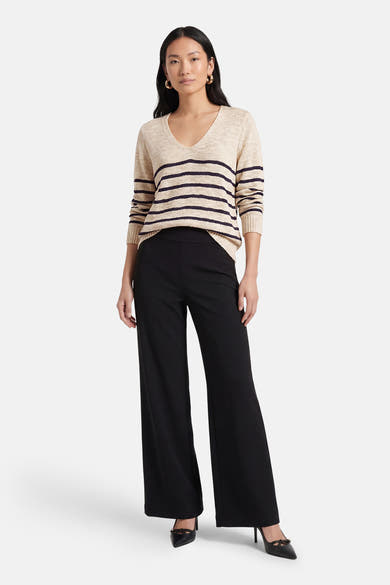 Pull à col en V multicolore de VILA®, avec des rayures horizontales, porté avec un pantalon noir évasé et des escarpins noirs.
