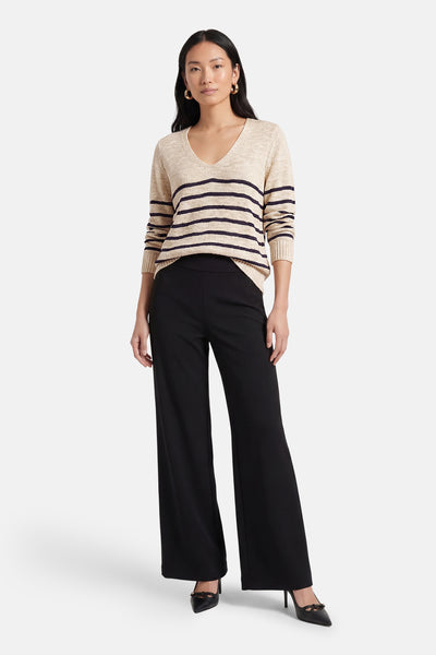 Pull à col en V multicolore de VILA®, avec des rayures horizontales, porté avec un pantalon noir évasé et des escarpins noirs.
