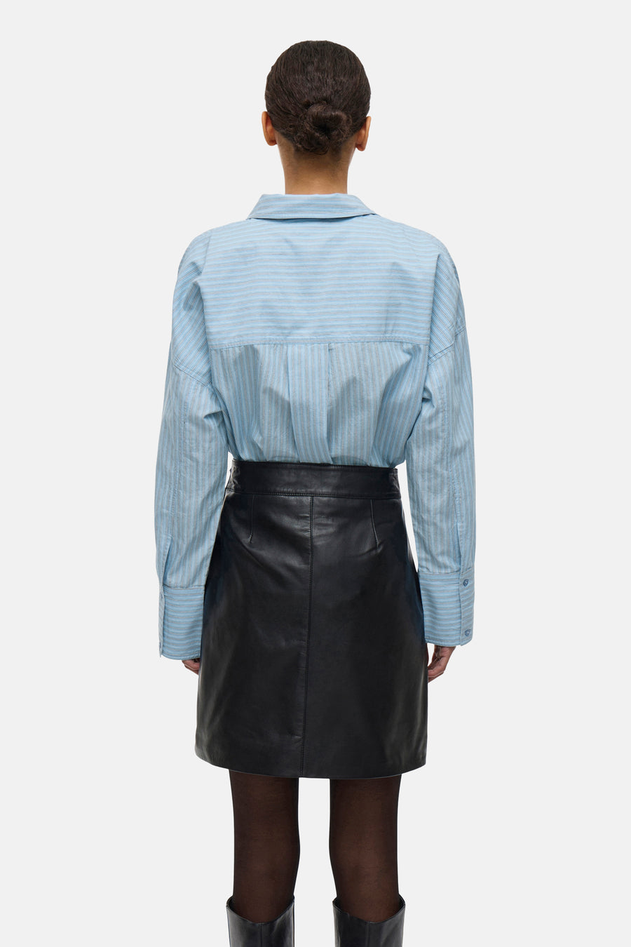 Chemise à manches longues bleue rayée de ROUGE EDIT, portée avec une jupe noire en cuir, vue de dos.
