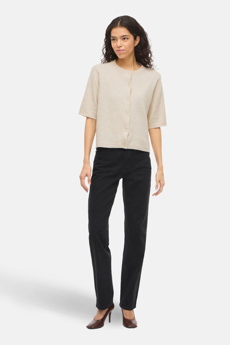 Gilet beige par VILA, porté avec un jean noir et des escarpins marron.