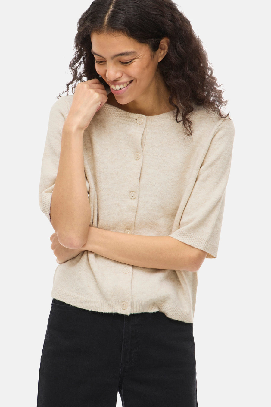 Beige gebreid vest van VILA®, met knopen, gedragen met een zwarte broek.