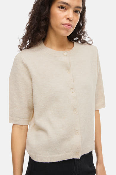 Beige vest van VILA®, met korte mouwen en knopen, gedragen met een zwarte broek.