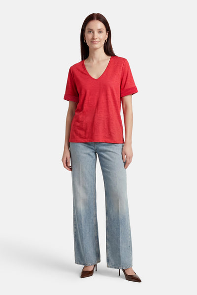 T-shirt rouge à manches courtes de VILA, porté avec un jean ample et des escarpins marron.
