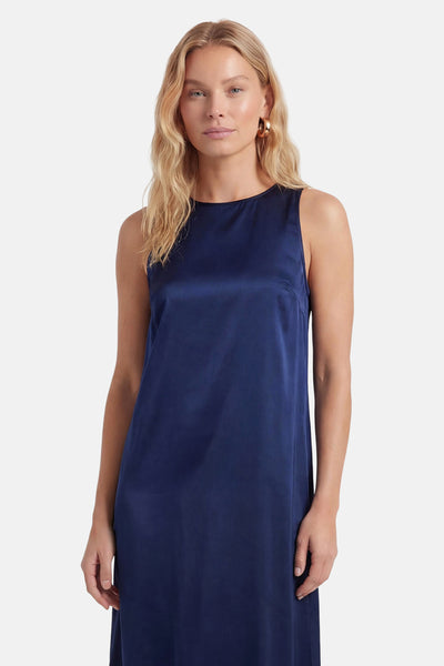 Robe bleu marine satinée de VILA®, sans manches, col bateau, portée par une mannequin avec des boucles d'oreilles dorées.