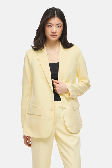 Blazer jaune de VILA, porté avec un haut noir, et un pantalon assorti.