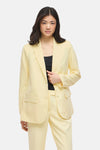 Blazer jaune de VILA, porté avec un haut noir, et un pantalon assorti.