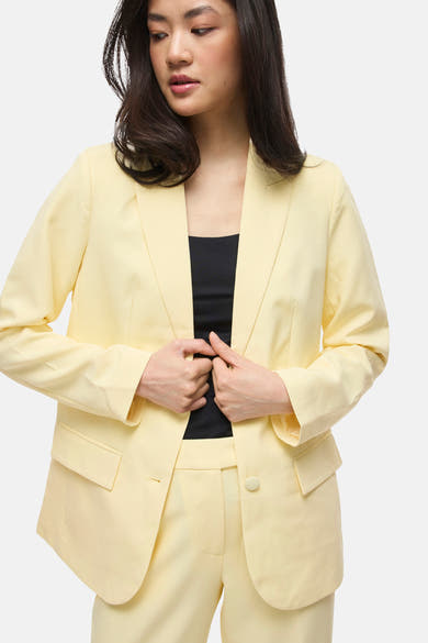 Blazer jaune de VILA, porté avec un haut noir uni.
