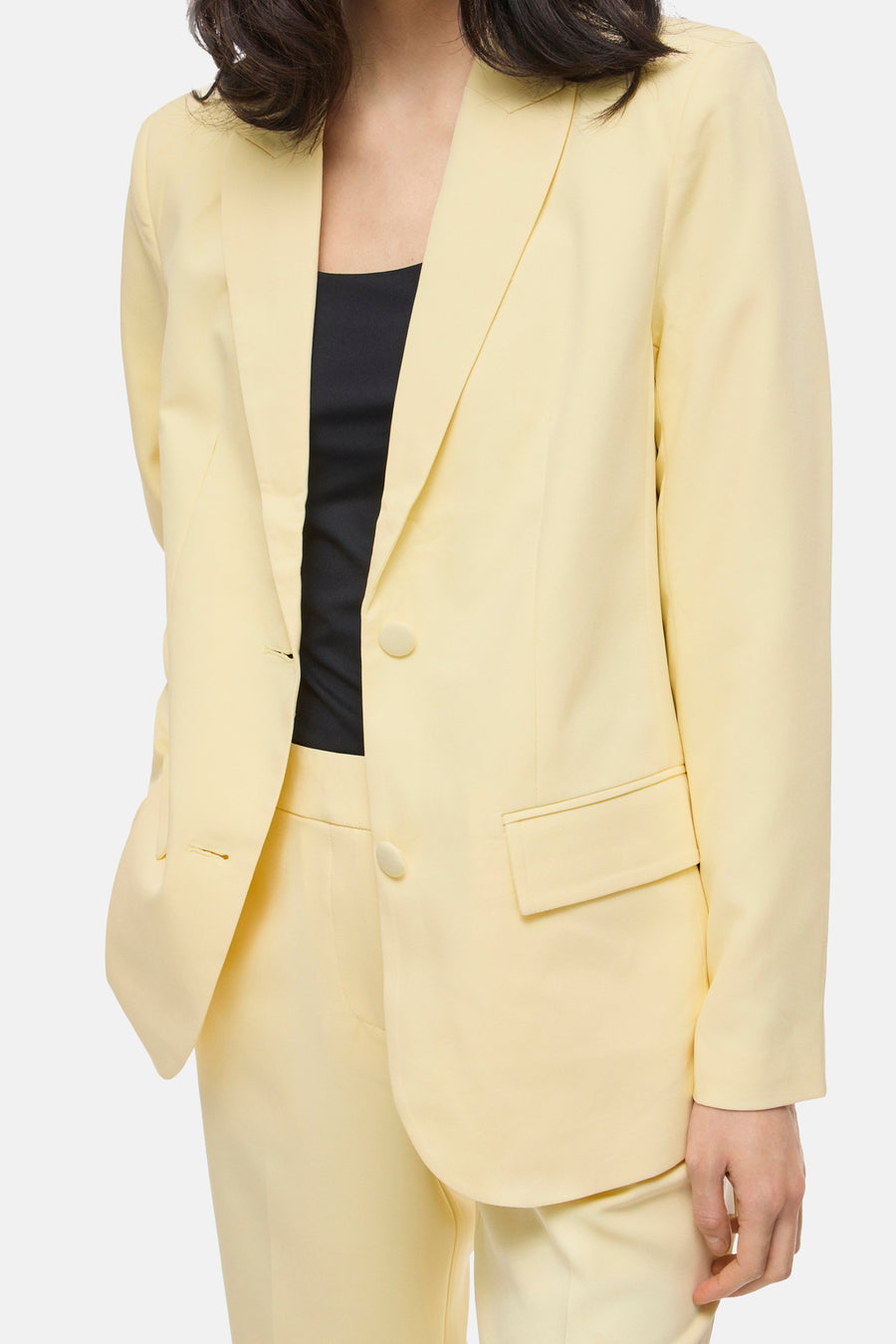 Blazer jaune de VILA, porté sur un haut noir, avec pantalon assorti et coupe classique.