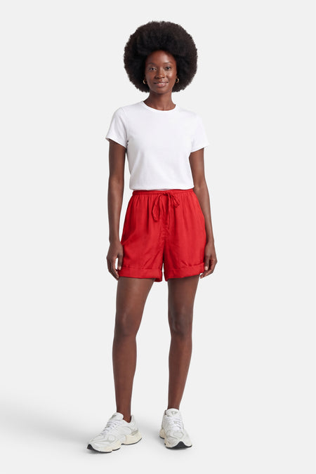 Korte oranje short van VILA met trekkoord en omslag, gedragen door een vrouw in een wit T-shirt en sneakers.