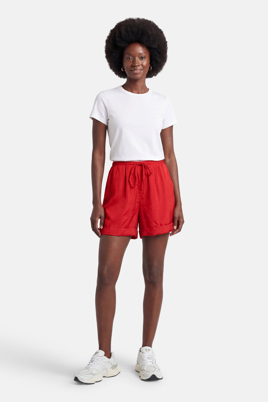 Korte oranje short van VILA met trekkoord en omslag, gedragen door een vrouw in een wit T-shirt en sneakers.