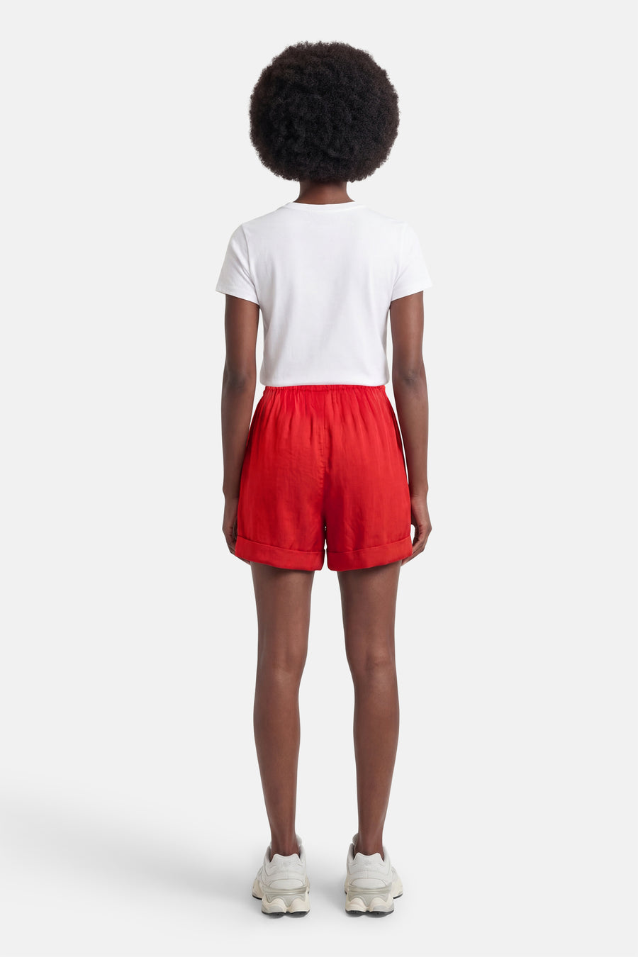 Korte rode short van VILA® met omgeslagen zomen, gedragen op de rug met een wit T-shirt en sneakers.