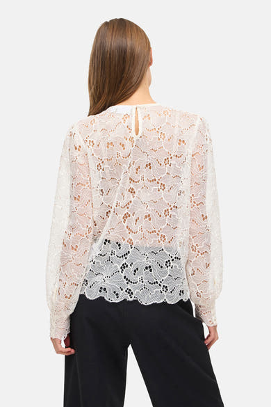Wit overhemd met lange mouwen van VILA®, in delicate kant met een opengewerkt bloemenpatroon, gedragen met een zwarte broek.