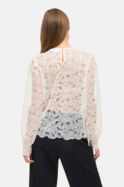 Chemisier blanc à manches longues de VILA®, en dentelle délicate avec motif floral ajouré, porté avec un pantalon noir.