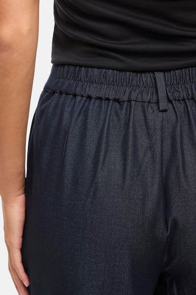 Pantalon bleu de VILA®, taille élastique avec cordon, porté avec un haut noir côtelé.