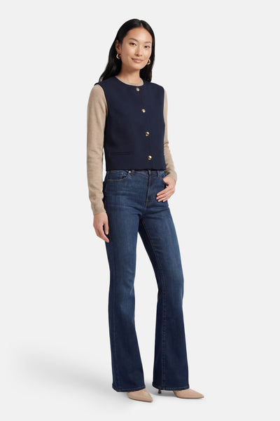 Blazer bleu VILA®, porté avec un pull beige à manches longues et un jean évasé.
