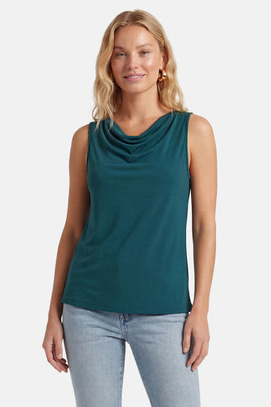 Top vert sarcelle sans manches de VILA avec col bénitier, porté avec un jean et des boucles d'oreilles dorées.
