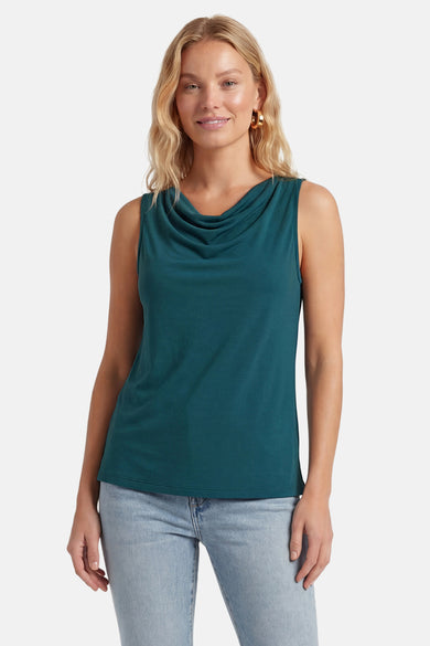 Top vert sarcelle sans manches de VILA avec col bénitier, porté avec un jean et des boucles d'oreilles dorées.