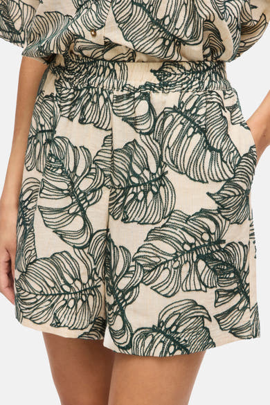 Short beige et vert foncé de VILA, avec broderie de feuilles tropicales et taille élastiquée.