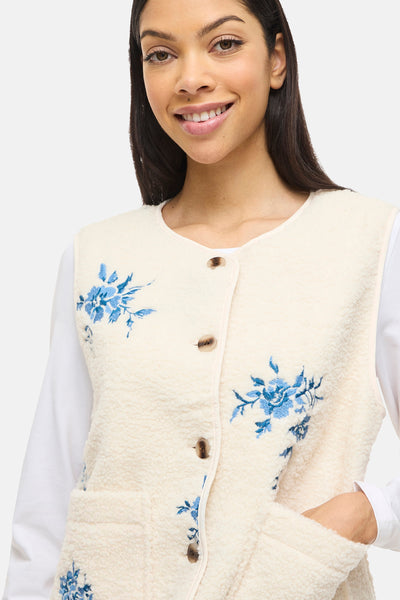Beige mouwloos vest van VILA®, met geborduurde blauwe bloemenpatronen en een bouclétextuur.
