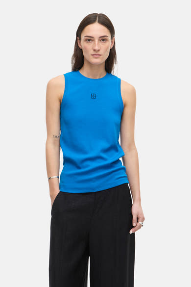 Top sans manches bleu de ROUGE EDIT, en maille côtelée, porté avec un pantalon noir ample.
