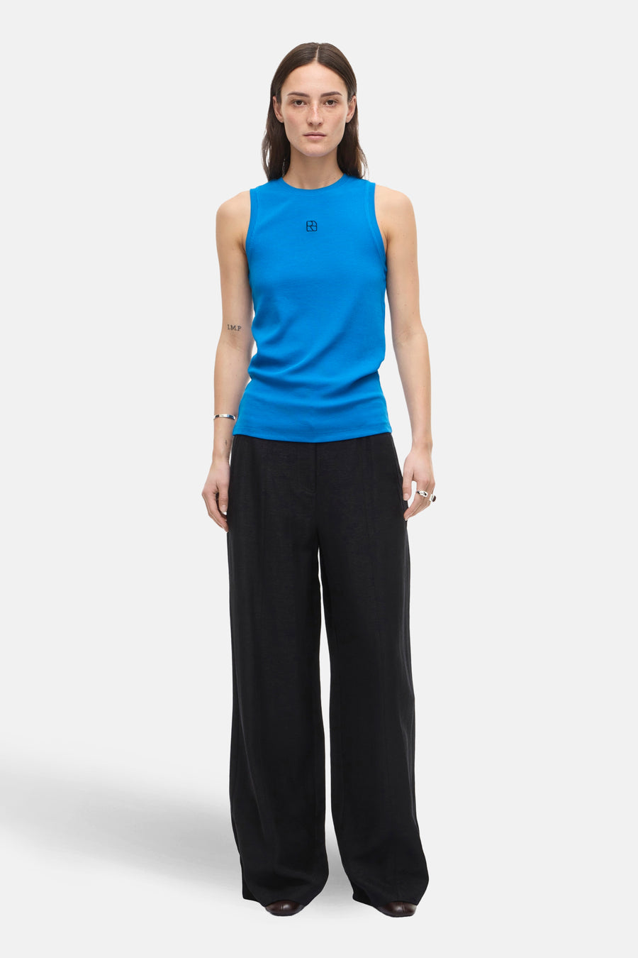Top sans manches bleu de ROUGE EDIT avec un logo discret, porté avec un pantalon noir fluide.