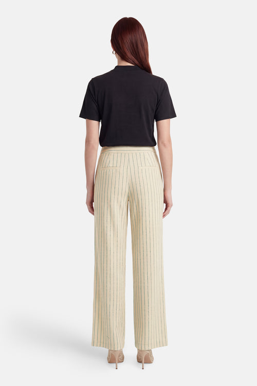 Pantalon multicolore de VILA, crème à rayures vertes verticales, coupe large, vu de dos avec un t-shirt noir et des talons beiges.
